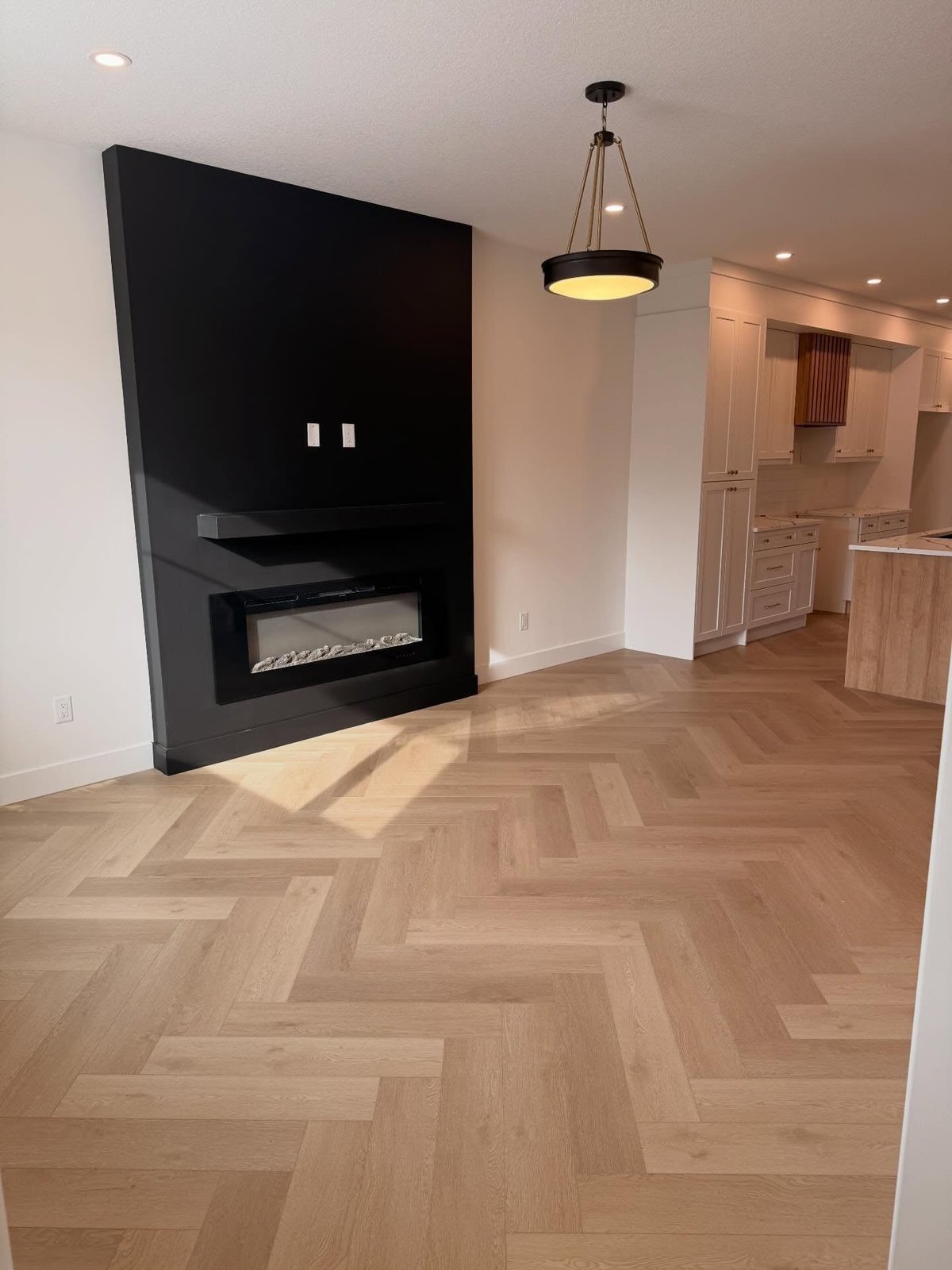 Light wood-look planks arranged in a herringbone pattern across an open living area.
