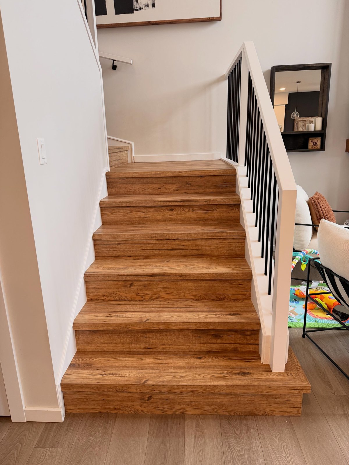 Brown laminate stair treads and risers with a turning step at the top of the flight.