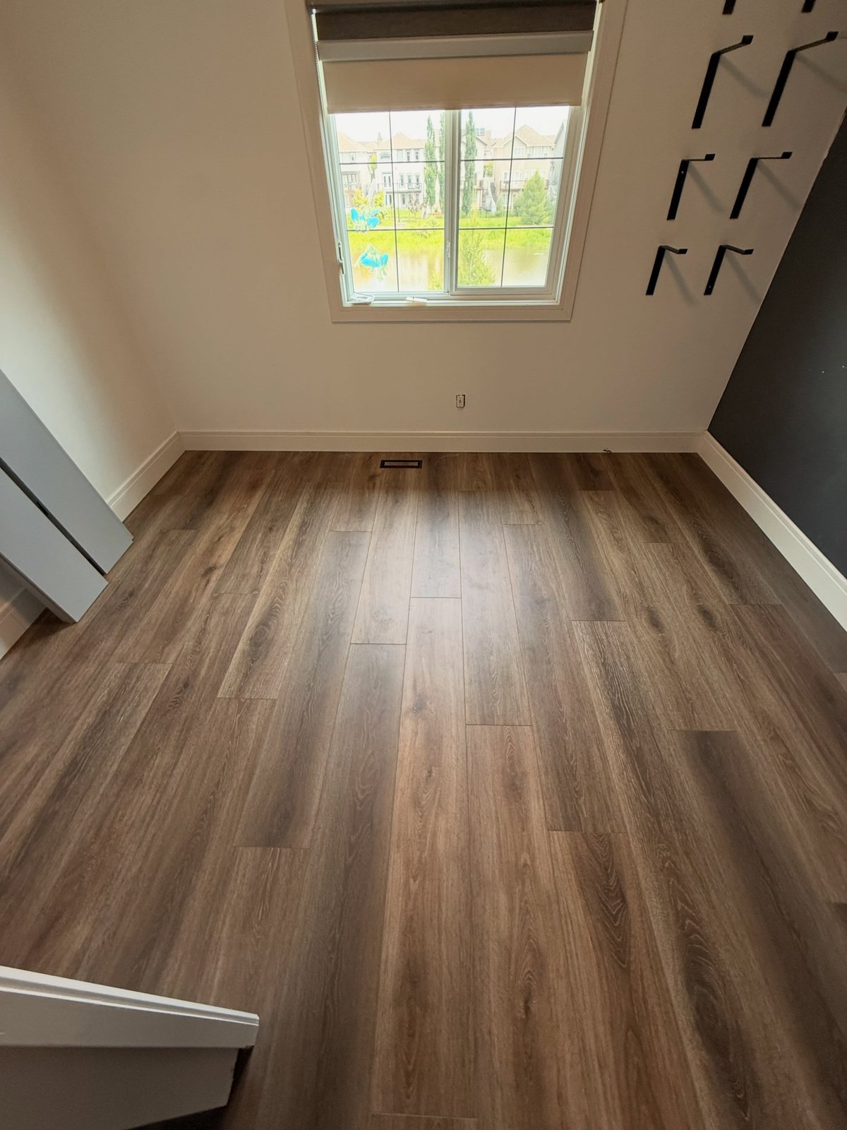 Brown wood-look planks with varied grain, laid lengthwise toward the window.