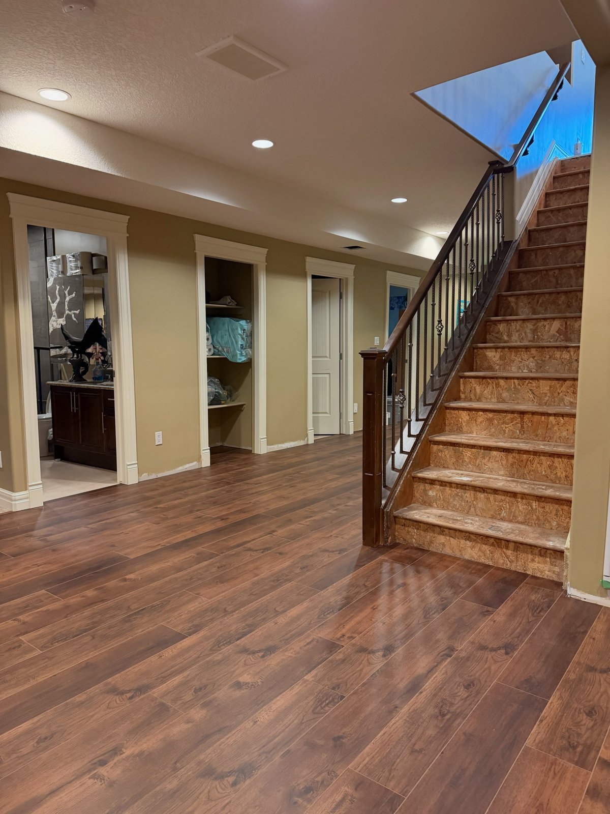 Dark wood-look planks with staggered joints, continuing to the base of an unfinished staircase.