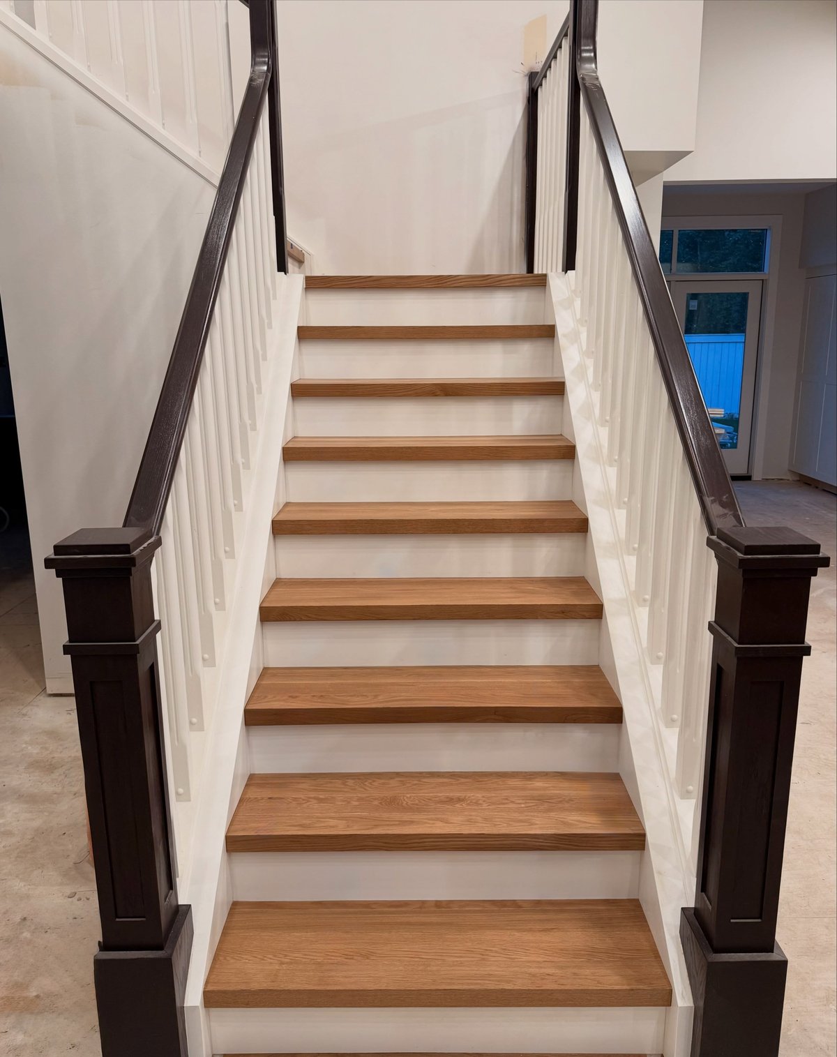 Straight staircase viewed from below, with brown wood-toned treads and white risers.