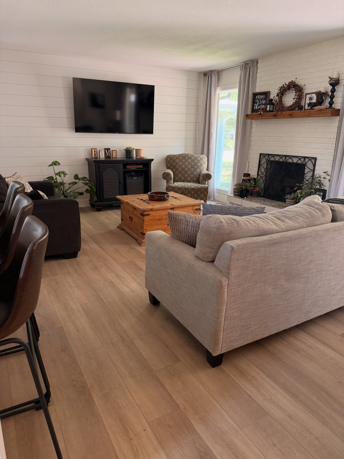 Light tan plank flooring with staggered joints around a sofa in a furnished living room.