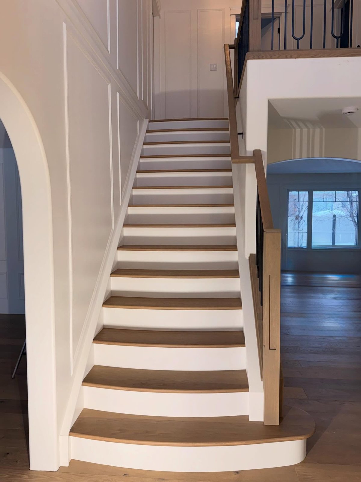 Custom curved hardwood stair treads with white risers and a rounded lower step, viewed from below.